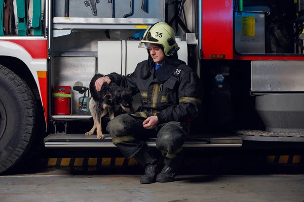 Foto do bombeiro no capacete com cão — Fotografia de Stock