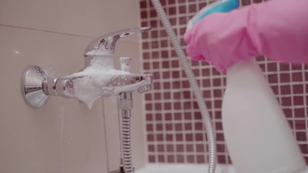 Крупный план женских рук в резиновых перчатках, чистящих раковину в ванной и кран. Концепция уборки дома . — стоковое видео