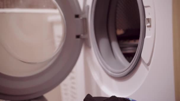 Женщина загружает стирку в стиральную машину — стоковое видео