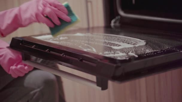 Молодая женщина чистки духовки — стоковое видео