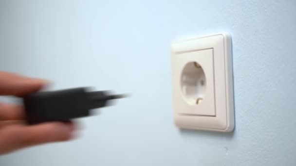 Mulher mão plug adaptador carregador de telefone preto na tomada de parede . — Vídeo de Stock