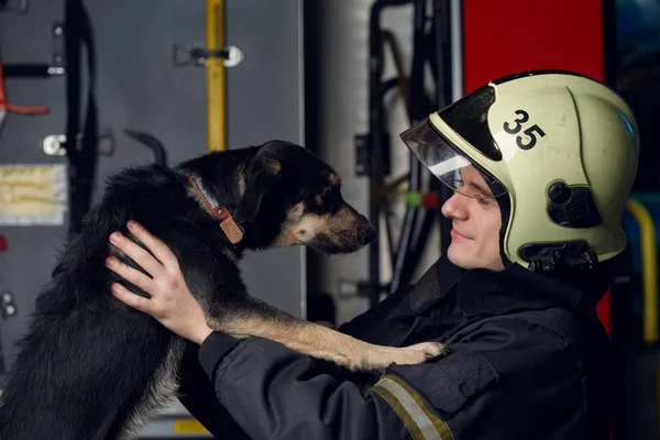 Beeld van de man brandweerman met hond bij brandweerwagen — Stockfoto