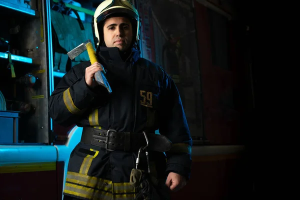 Photo of man firefighter with pick near fire truck