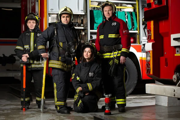 Изображение трех пожарных мужчин и женщин возле пожарной машины — стоковое фото