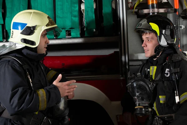 İki itfaiyeci adam itfaiye arabası yakınındaki tarafında fotoğraf