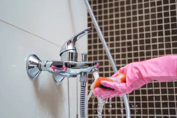 Woman s hand in pink rubber gloves washing bathtub mixer — Stock Photo, Image