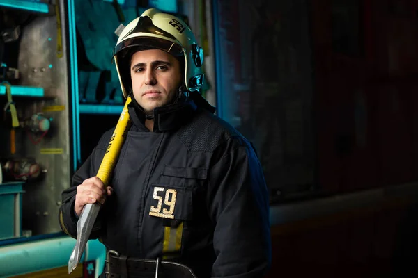 Image of man firefighter with pick near fire truck