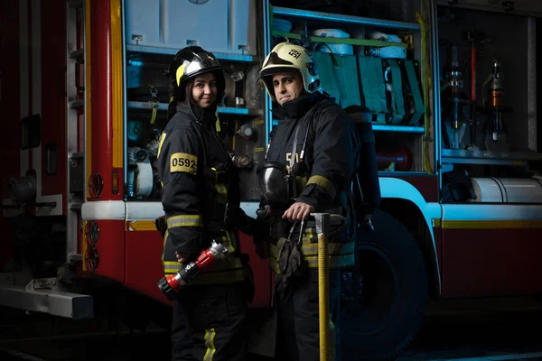 Foto muž a žena hasiče na hasičský vůz — Stock fotografie