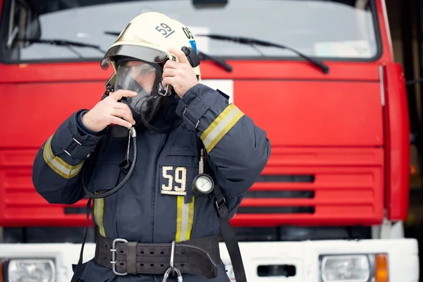 Foto di uomo pompiere in maschera antigas vicino camion dei pompieri — Foto Stock