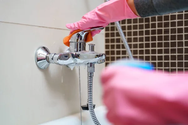 Mano donna in guanti di gomma con detergente miscelatore per vasca da bagno — Foto Stock