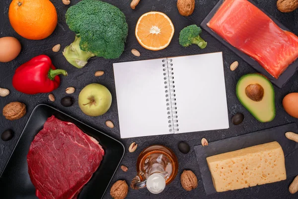 Immagine di prodotti alimentari per la dieta, blocco note pulito sul tavolo di pietra nera . — Foto Stock