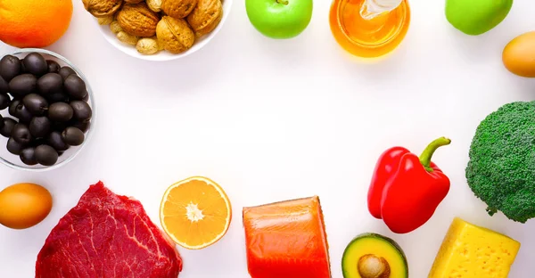 Foto auf einem Stück Fleisch, Fisch, Käse, Eier, Gemüse, Obst, Oliven, Walnüsse auf weißem Hintergrund. — Stockfoto