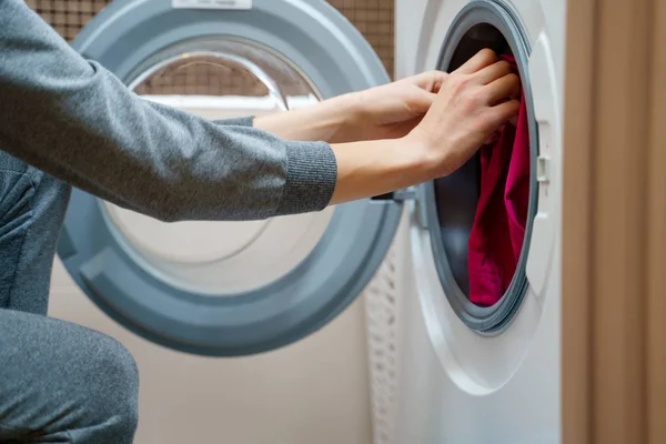 Image of woman folding clothes into washing machine — Stock Photo, Image