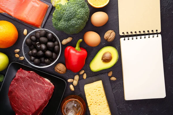 Bild von Diätprodukten, leeres Notizbuch auf schwarzem Steintisch. — Stockfoto