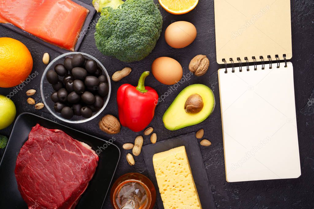 Image of products for diet, empty notebook on black stone table.