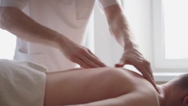 Närbild av terapeuten gör ryggmassage en attraktiv man att ha en ryggmassage — Stockvideo