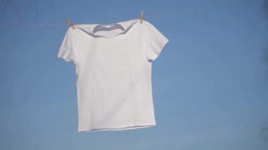 Mavi gökyüzü karşı clothesline asılı T-shirt