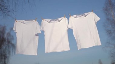 Mavi gökyüzü karşı clothesline asılı T-shirt