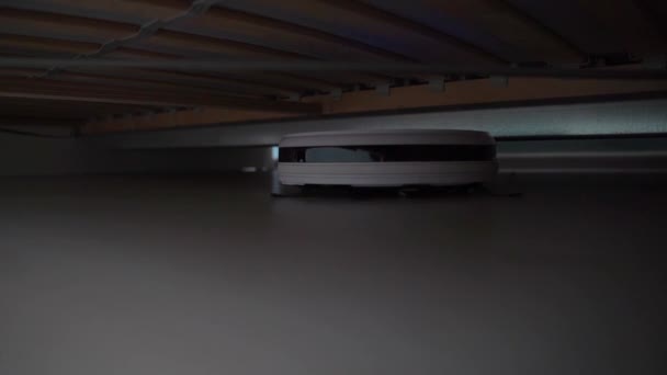 The robot vacuum cleaner cleaning under the bed — Stock Video