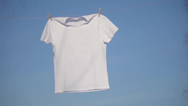 Camisetas colgando en el tendedero contra el cielo azul — Vídeo de stock