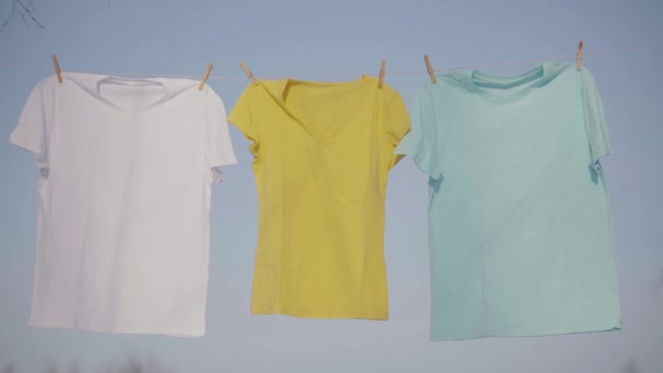 T-shirts opknoping op de waslijn tegen blauwe hemel — Stockvideo