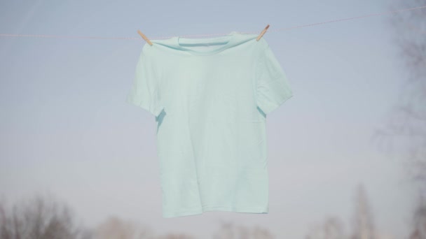 T-Shirts hängen an der Wäscheleine vor blauem Himmel — Stockvideo