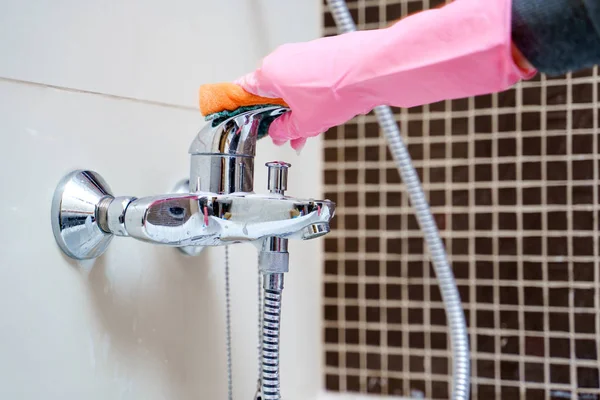 Bild av kvinnans händer i rosa gummihandskar tvätt badkar blandare — Stockfoto
