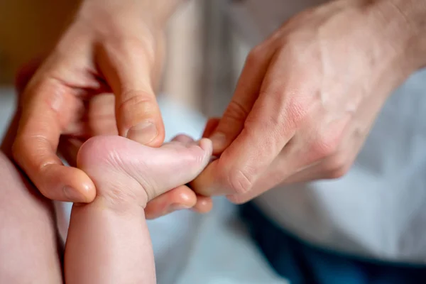 Picture of hands of massage therapist making foot massage to small child.