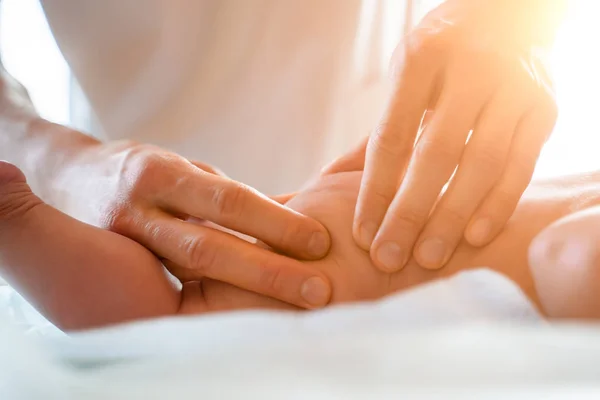 Masseur faz massagem nos pés para criança pequena, deitado no estômago na mesa . — Fotografia de Stock