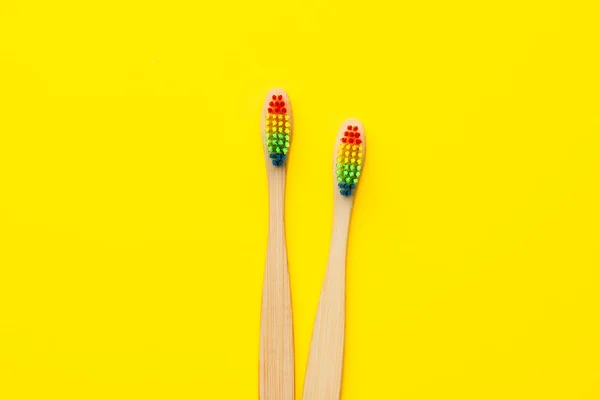Imagen de dos cepillos de dientes de madera con cerdas de color arco iris . —  Fotos de Stock