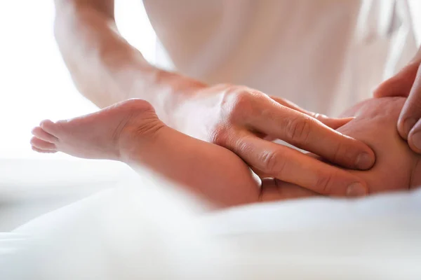 Male masseur doing small childs leg massage, lying on table. — Stock Photo, Image