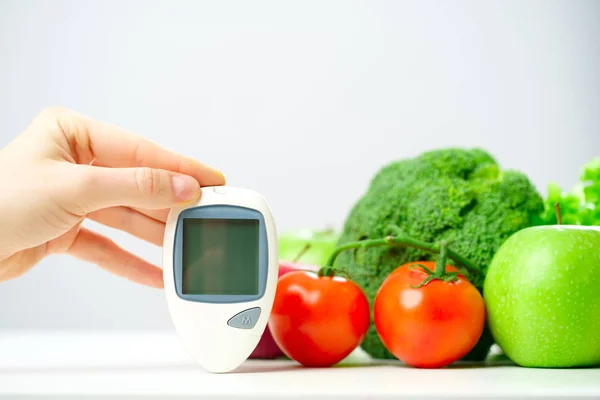 Photo of mans hand with glucometer near apples, tomato, broccoli . — Stock Photo, Image