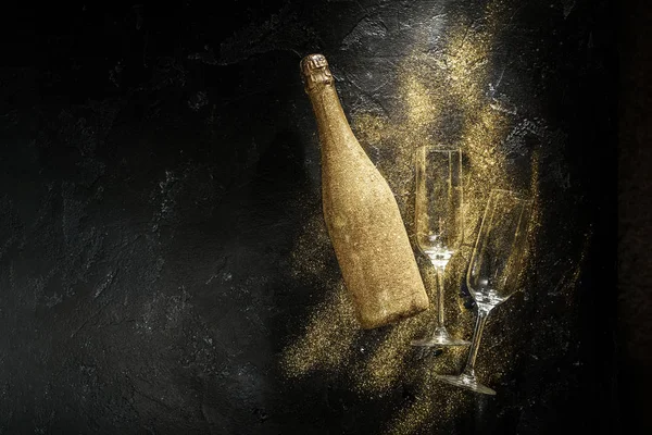 Romantic photo of golden champagne bottle, two wine glasses on black stone background — Stock Photo, Image