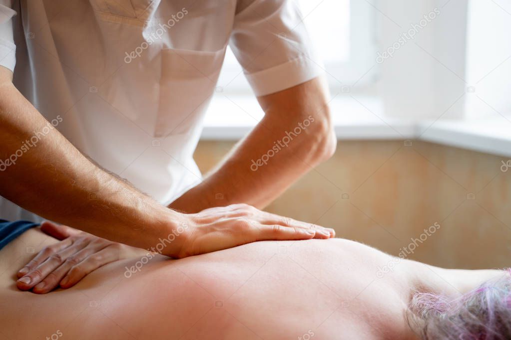 Masseur doing massage of back young girl.