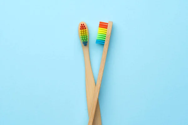 Foto von zwei hölzernen Zahnbürsten mit regenbogenfarbenen Borsten . — Stockfoto