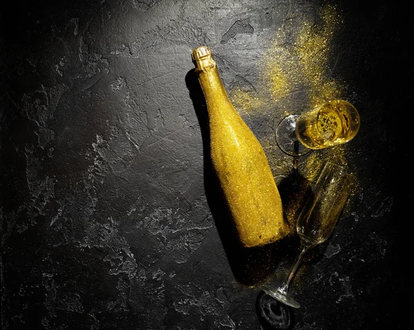 Romantic image of golden champagne bottle, two wine glasses on black background — Stock Photo, Image