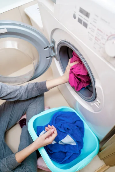 Foto de arriba de las manos femeninas poniendo ropa sucia rosa en la lavadora  . — Foto de Stock