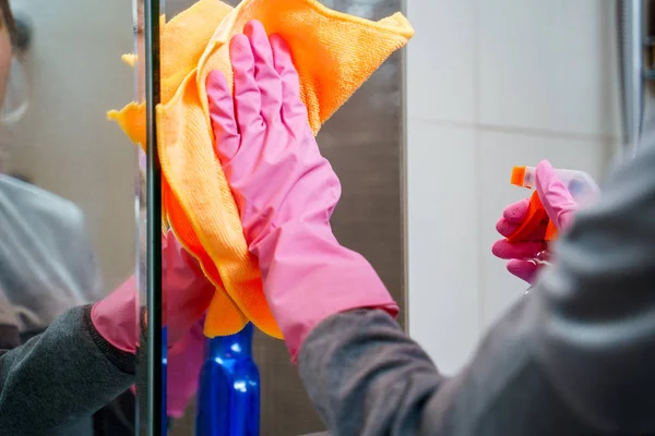 Imagen de las manos femeninas en guantes de goma con trapo y limpiador espejo de lavado en el baño . — Foto de Stock