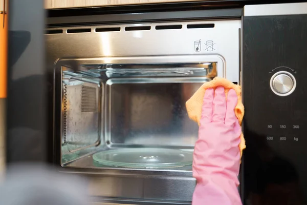 Kép a kezét a gumikesztyűt, mosógép, mikrohullámú sütő — Stock Fotó