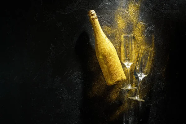 Romantic picture of golden champagne bottle, two wine glasses on black stone background — Stock Photo, Image