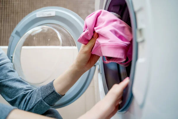 Mujeres manos poniendo la ropa en la lavadora — Foto de Stock