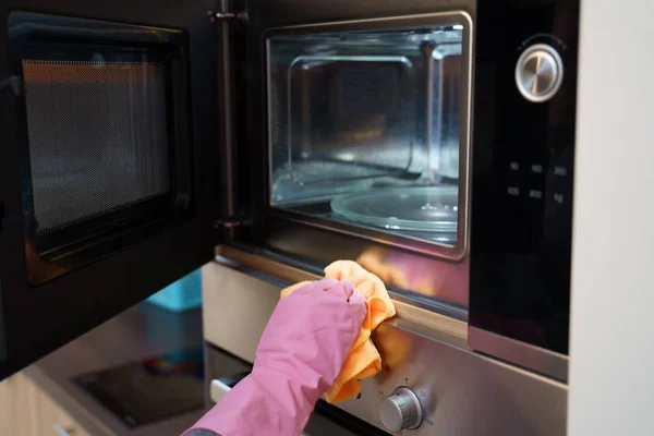 Фото рук в резиновых перчатках, стирающих микроволновку — стоковое фото
