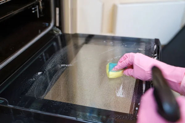 Foto de la mujer en el horno de lavado guantes de goma rosa . — Foto de Stock