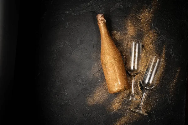 Romantic photo of golden champagne bottle, two wine glasses on black stone background — Stock Photo, Image