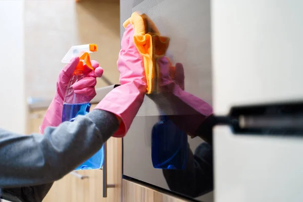 Imagen de las manos de mujer en guantes de goma con trapo y detergente limpieza microondas . — Foto de Stock