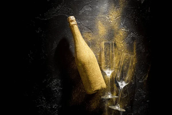 Romantic image of golden champagne bottle, two wine glasses on black stone background — Stock Photo, Image