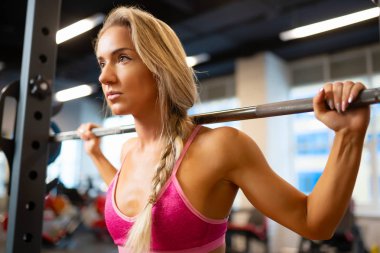 Halter salonunda omuzlarında ile sportif sarışın ayakta portresi.