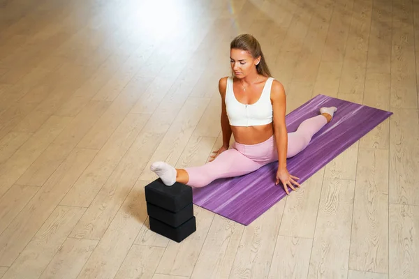 Young sportswoman doing splits on mat. — Stock Photo, Image