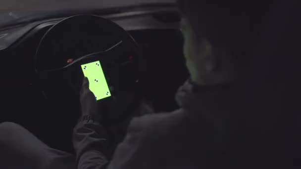 El hombre se sienta en el coche viejo y sostiene el teléfono inteligente con pantalla verde. Clave de croma . — Vídeo de stock