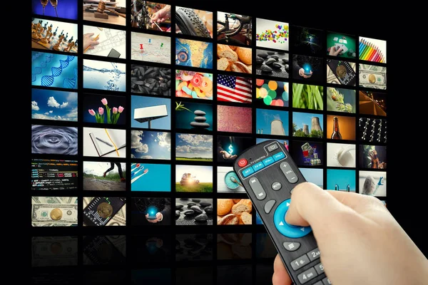 TV set with lot of pictures and hands of man with remote control on empty black background — Stock Photo, Image